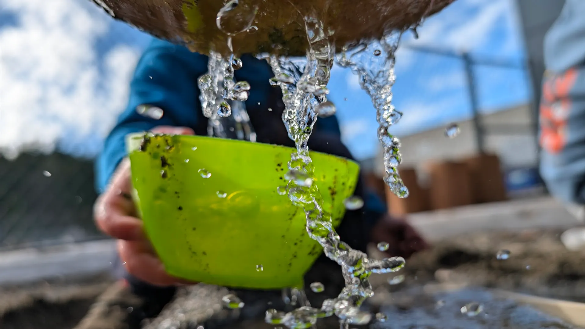 A child pouring water into a bowl during outdoor sensory play at Comfort First Early Learning
